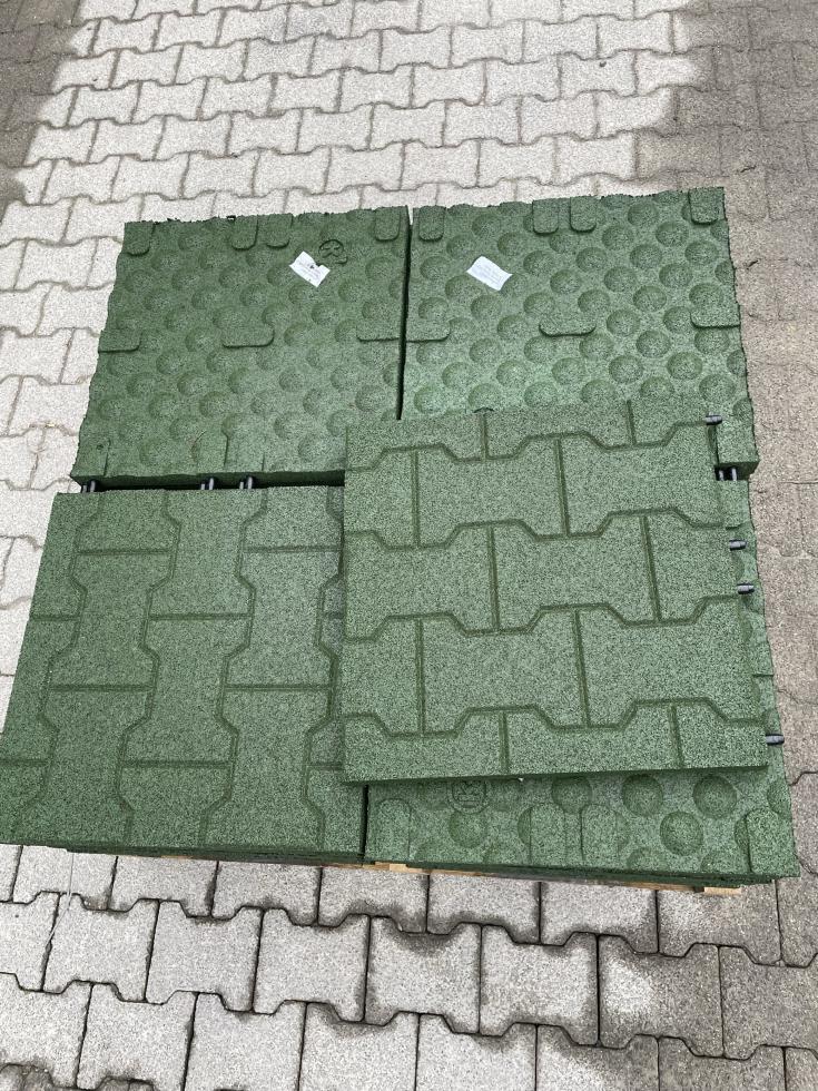 Pferdeauslauf mit Abtrennungen unterteilt, ausgelegt mit quadratischen Platten aus mehreren, roten Komfortexpflastersteinen, links begrenzt durch Betonmauer, rechts ist eine weisse Stallwand, oberhalb des Betonmäuerchens auf der linken Seite, beginnt eine Wiese, die wiederum in einem Wald endet am hinteren Ende befinden sich weiss eingepackte, aufgetürmte Strohballen