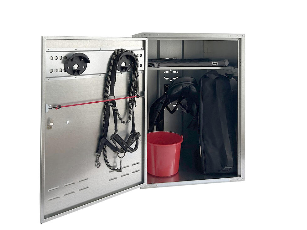 Ein Sattelschrank verzinkt geöffnet mit zwei Trensenhalter auf der Innenseite der Türe und ein Tablar im Hauptteil, resultierend in zwei Fächern, von welchen im grösseren und unteren ein schwarzer Sat