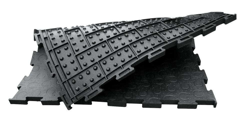 Ein komplettes, quadratisches Stück einer schwarzen Puzzlematte aus Gummi mit Hufeisenprofil, zur Hälfte umgeklappt, sodass das Profil der unteren Seite sichtbar wird, Rechtecke mit jeweils 8 Noppen pro Rechteck, Draufsicht
