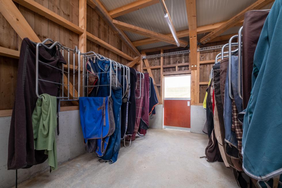 zwei Deckenhalter mit jeweils sechs Aufhängungen an weisser Wand montiert, metallic Rohrgestänge, voll behängt mit Schabracken, Ansicht von vorne