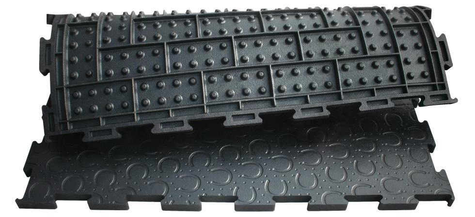 Ein komplettes, quadratisches Stück einer schwarzen Puzzlematte aus Gummi mit Hufeisenprofil, zur Hälfte umgeklappt, sodass das Profil der unteren Seite sichtbar wird, Rechtecke mit jeweils 8 Noppen pro Rechteck, Draufsicht