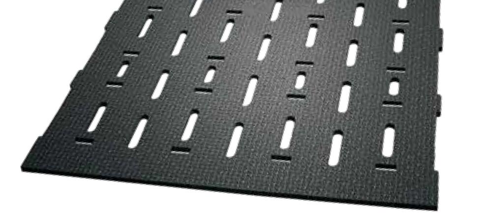 Eine schwarze Gummimatte mit Längsschlitzen, quere kurze Spalten, als Ausspaarung für Kunststoffzapfen