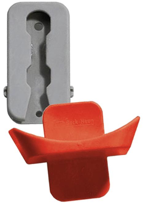 Ein Scharnier aus grauem Kunststoff, einzelne Metallkomponenten sichtbar, zwei Aussparungen zum Einhängen, Sicherheitsausschubsöffnung, leicht schräg unten und überlappend die halbrunde Auflage mit Rü