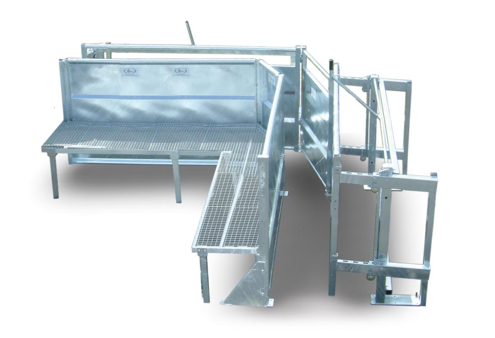 Ein Behandlungs- und Einfangstandstand mit Liegegitter und Schwenkachse, vorne zwei feste schwarze Räder, auf der Hinterseite ein schwarzes Brett, Schaf eingespannt umgedreht, wessen Klauen von einer Person geschnitten werden