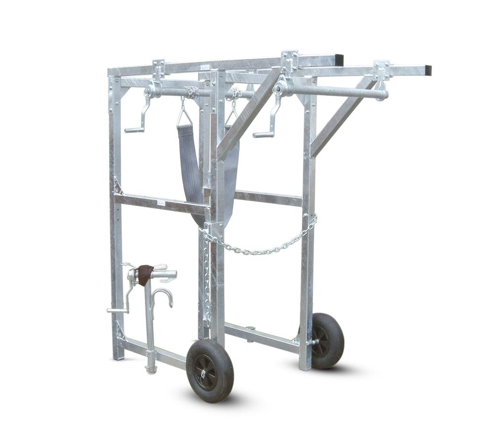 Ein Behandlungs- und Einfangstandstand mit Liegegitter und Schwenkachse, vorne zwei feste schwarze Räder, auf der Hinterseite ein schwarzes Brett, Schaf eingespannt umgedreht, wessen Klauen von einer Person geschnitten werden