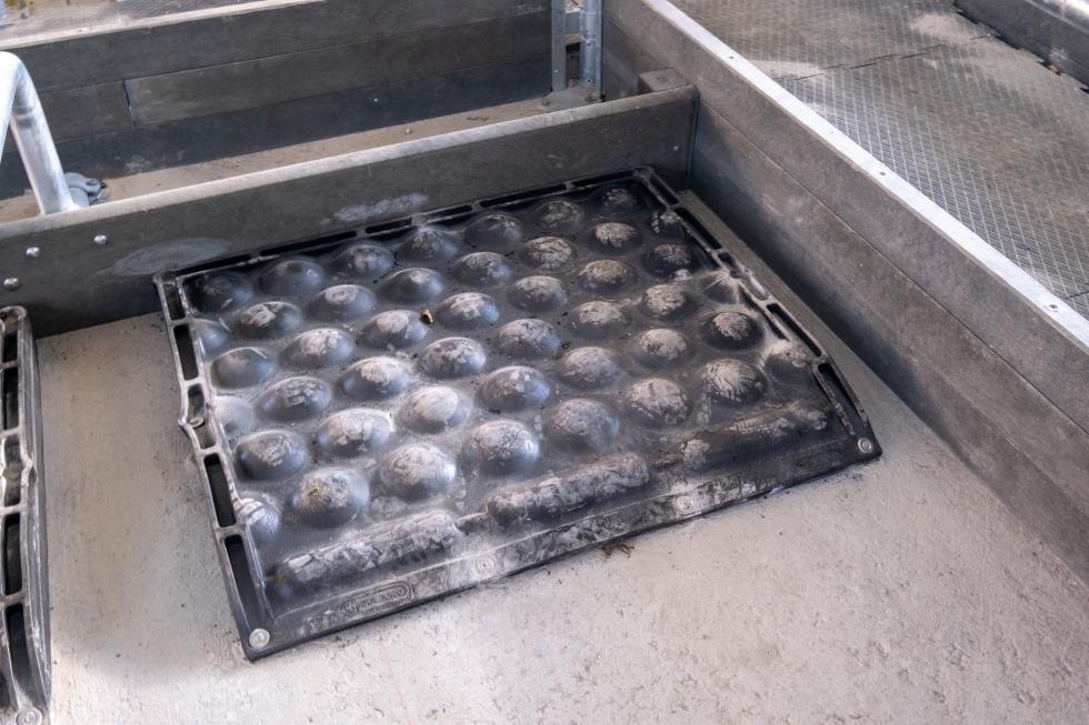 Ein schwarzes Tiefboxenkissen aus Gummi mit kugelartiger Ausstülpungen auf der Oberseite, gefüllt mit Luft, erhöhter Rand hinten und seitlich, pillenartige Ausstülpungen am vorderen Rand, dicker als herkömmliche Gummimatten, unter Einstreu in Tiefbox platziert in einem Stall