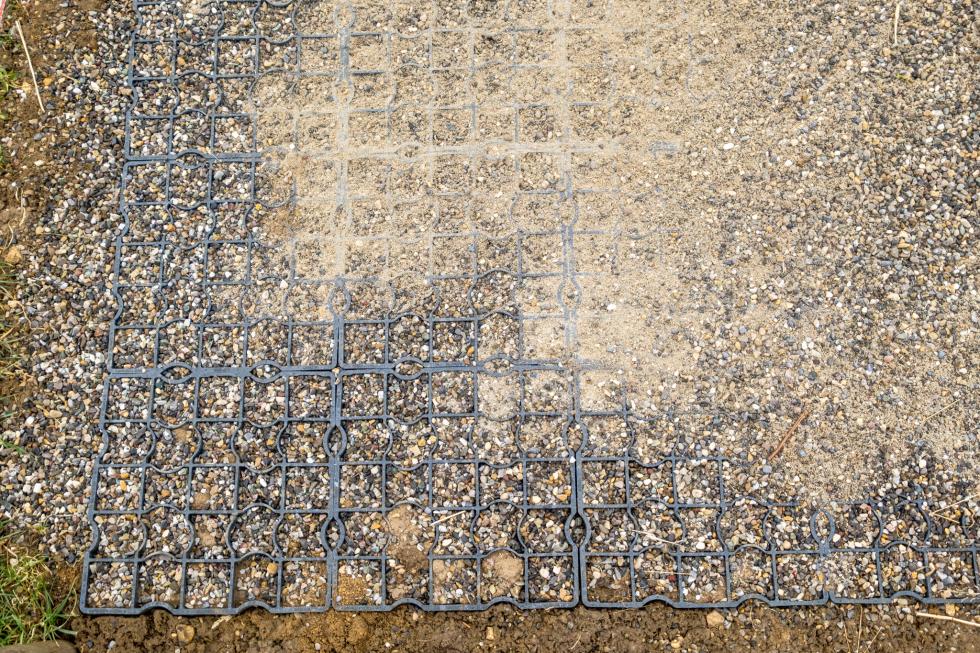 Boden bedeckt mitgrauen Kunststoffecoraster, untereinander verbunden mit Zäpfchen, bedeckt und gefüllt mit Kies in einem Aussenpferdeauslauf